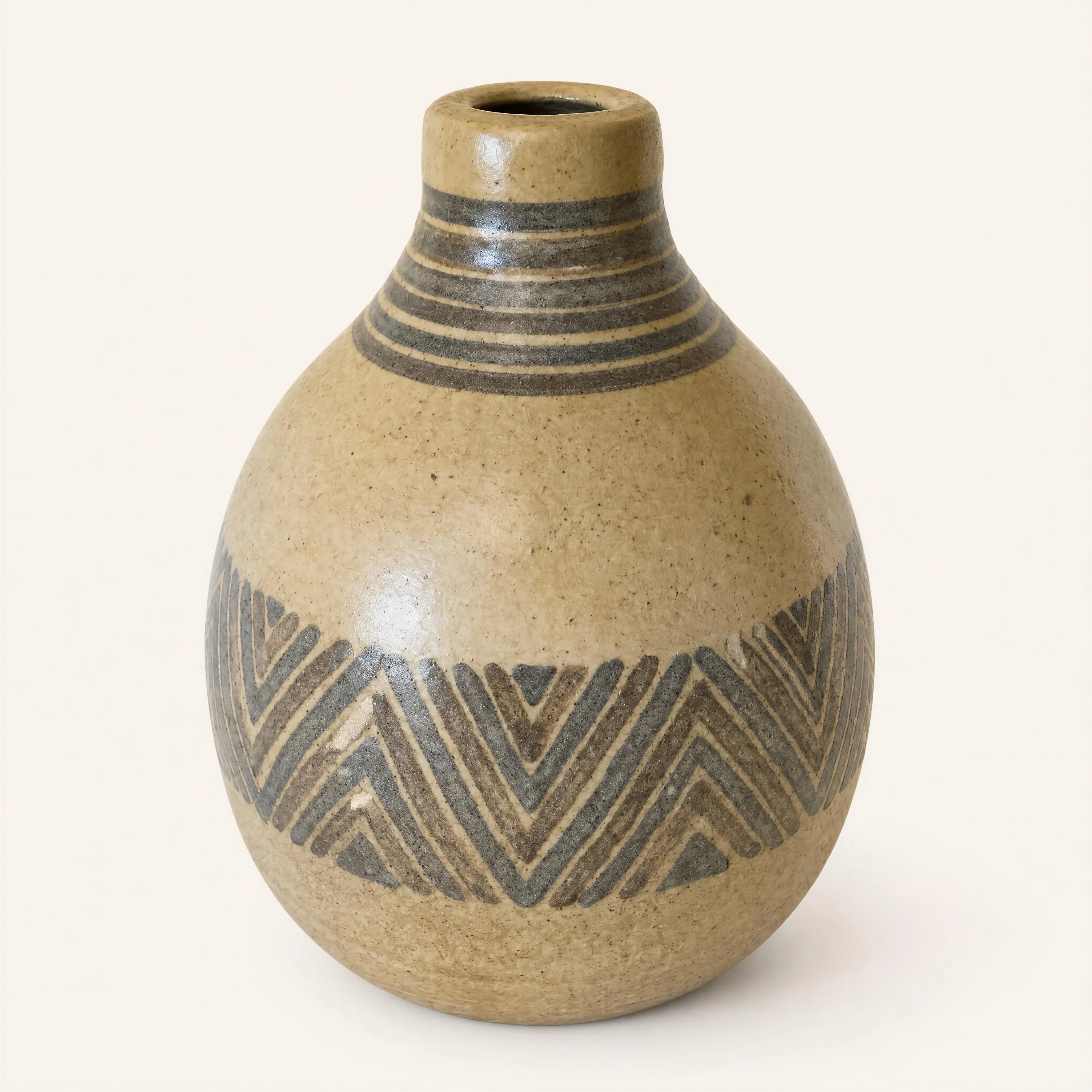 Vase en grès émaillé présentant une panse de forme globulaire et bombée. Le corps de la pièce se rétrécit dans sa partie supérieure pour dessiner un épaulement arrondi, surmonté d'un col court, étroit et cylindrique à lèvre droite. La couverte présente un émail beige clair moucheté de fines incisions et de ponctuations sombres inhérentes à la cuisson de la pâte.  
Le décor géométrique, peint dans une nuance gris-brun contrastante, est structuré en deux registres distincts. Le col et le haut de l'épaulement sont ceints d'une succession de lignes horizontales concentriques. La partie médiane de la panse est quant à elle ornée d'une large frise continue développant des motifs de chevrons et de triangles emboîtés formés de bandes parallèles.