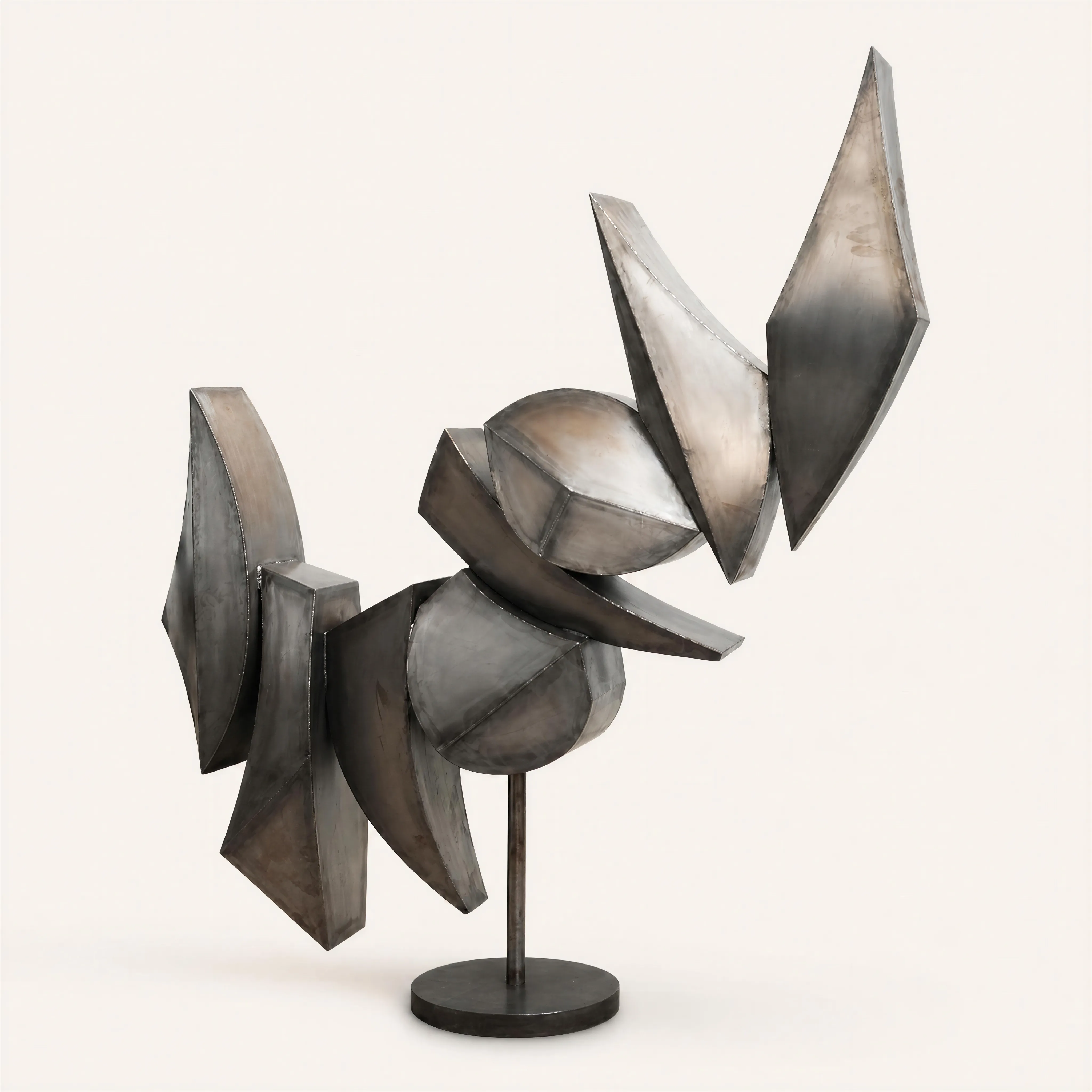 A large, monumental abstract iron sculpture designed to swivel on a central vertical axis anchored to a circular base. The dynamic composition features an assembly of interlocking geometric forms with sharp edges, planar facets, and conical elements, creating a stylized silhouette that suggests angular motion.