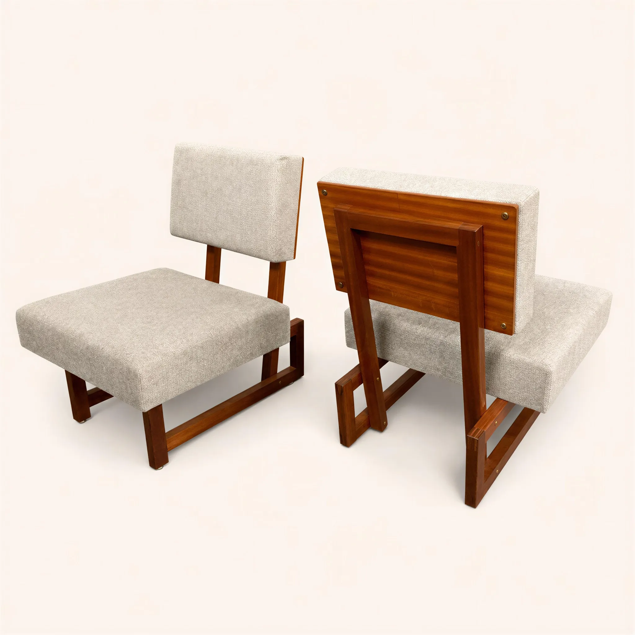 Pair of low armchairs in mahogany. The slanted seat and backrest are entirely covered in a gray fabric.

André Sornay developed a rapid furniture assembly system, filing various patents for it between 1953 and 1955. This patent, known as the "tigette Sornay," proved to be revolutionary. This process laid the foundation for the entire flat-pack or "kit" furniture system used today. The assembly of the piece is limited to joining a front frame and a rear frame fitted with threaded inserts designed to receive the rods. The nuts are left visible on the front facade.