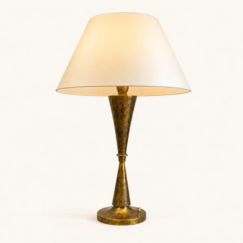 Lamp crafted from oxidized patinated brass. Its geometric stem consists of two opposing inverted conical forms, joined at the center by a ring. The upper section flares into a cup designed to hold the reflector and lampshade. The entire piece rests on a circular base featuring a scalloped rim at its bottom and equipped with an integrated push-button switch.

Unique piece (special commission).

Exhibition: Exhibited at the Pavillon du Luminaire in 1937.

Certificate: Accompanied by a certificate of authenticity from Jean-Marc Maury.