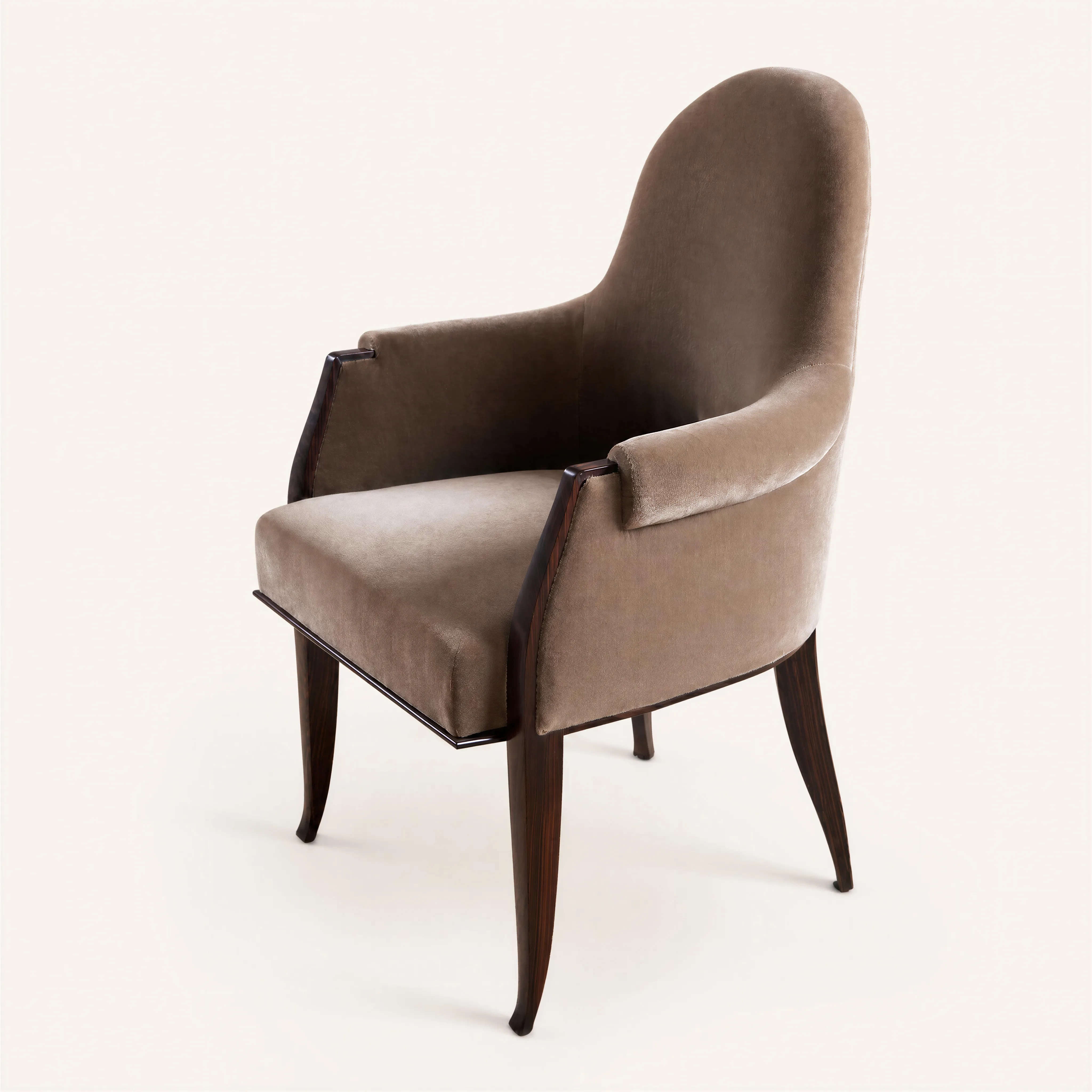 An armchair with a high, upright backrest rounded at the top. The solid armrests terminate in padded, outwardly scrolled cuffs.
The Macassar ebony frame is visible as a wooden trim outlining the front edge of the armrests and extending downward to encircle the base of the frame beneath the seat cushion. The support structure consists of four solid wood legs: the two front legs are tapered with a circular cross-section, while the two rear legs display an outwardly curved sabre profile. The entire inner and outer surfaces of the backrest, sides, and seat are covered in velvet padding.  
llustrated on page 335 in the book “Ruhlmann” by Florence Camard, Édition Monelle Hayot, 2009. 